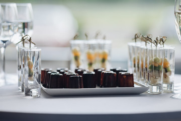 Closeup of delicious healthy appetizers served on birthday party. Selective focus of sweet bananas, kiwi, and oranges in glasses. Concept of catering, desserts, arrangement and decoration.
