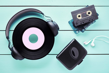 Vintage vinyl record, headphones, earphones, cassette player and cassettes on wooden table