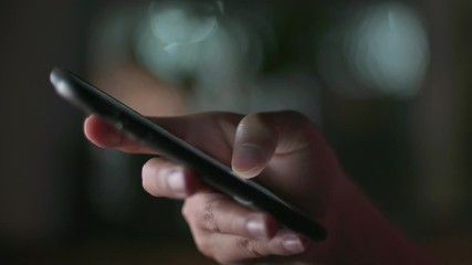 Gadget technology or communication concept : Close up woman hands using smart phone in dark room in front of computer monitor. - Powered by Adobe