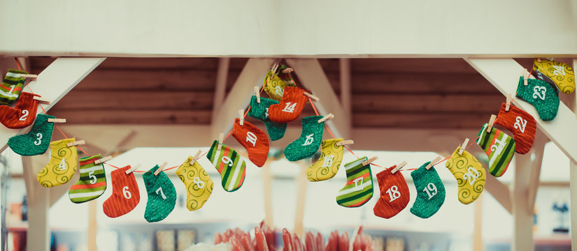 Advent calendar. Christmas decoration bright and colorfull stockings hanging over wooden background. Traditional festive decor. Wide banner. Selective focus, copy space.