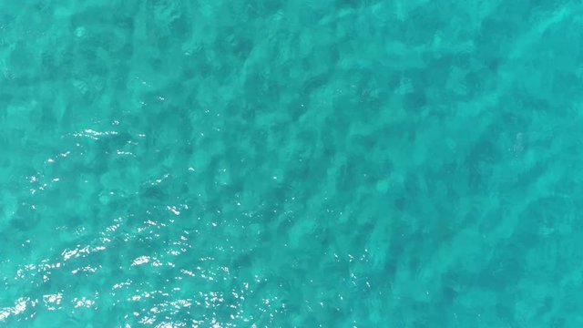 Aerial top down view. Calm clear blue sea water background. 4K