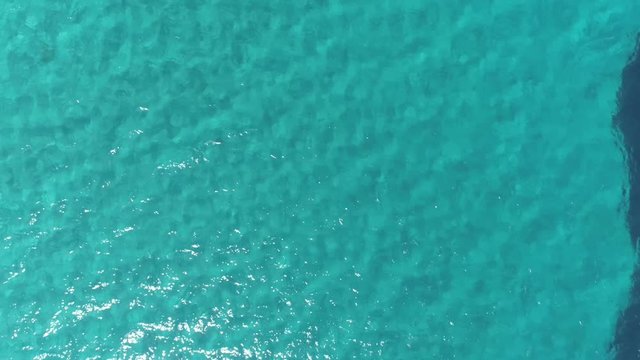 Aerial top down view. Calm clear blue sea water background. 4K