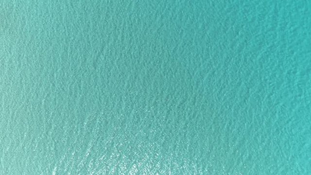 Aerial top down view. Calm clear blue sea water background. 4K