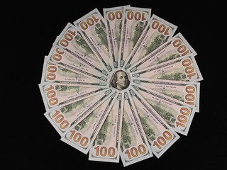 Banknotes of 100 US dollars lie in a circle. The image of Benjamin Franklin is surrounded by hundred-dollar bills. American money on the table. Concept: currency, dollar exchange rate