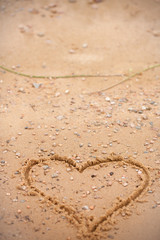 Photo postcard from the beach. Beach holidays, concept with hearts. A vertically oriented photo background with a finger drawn heart on a beach sand.