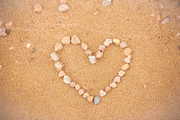 Fototapeta na wymiar Heart on the beach. Love on the beach. Romantic photo concept with a heart made of stones in the sand, layout with copy space on the theme of love, Valentine's day, wedding, beach holiday and various 