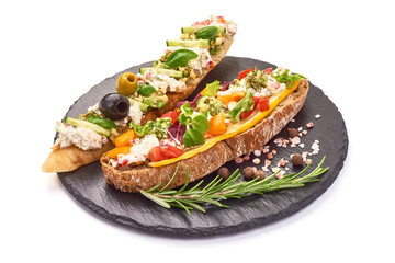 Spanish Tapas and Pinchos with cottage cheese, tomatoes, cucumber, olives, garlic and herbs, Italian Bruschetta on a stone plate, isolated on white background