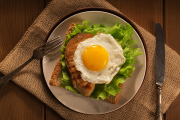 Fried egg and chicken on bread for breakfast on plate and rustic table