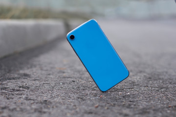 Crash test of a new mobile phone. Gadget falling and crashes on asphalt, floor. Broken smartphone flying down to the ground. Smashed, destroyed, damaged cell phone. Accident with blue device. Failure. © Евгений Шемякин