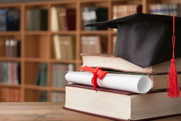 Graduation hat on stack of books and diploma