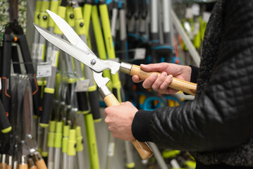 Man is buying a new gardening scissors in a garden store.