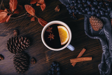 Mulled wine with spices, grapes, pine cones, cinnamon and oranges on a dark wooden background