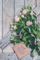 a bouquet of roses with a note on a wooden table