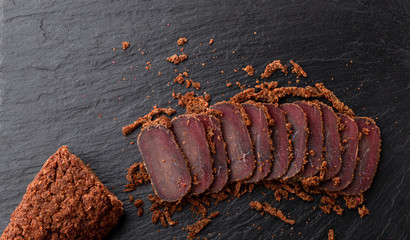 Cured meat on a slate board. Close-up of basturma sliced into pieces.