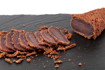 Cured meat on a slate board. Close-up of basturma sliced into pieces.