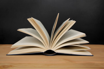 open paper book with open pages, reading concept, on a wooden table, horizontal, closeup, copy space