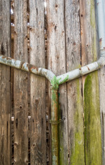 Marodes Wasserrohr an alter Bretterwand