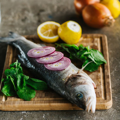 Fresh raw fish and food ingredients on table. Raw fish with spices on wooden cutting board. Top view