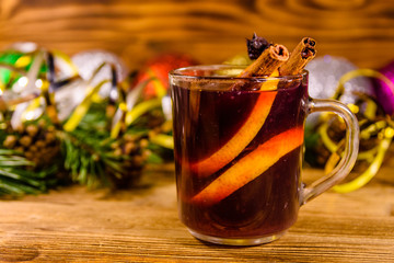 Cup of mulled wine with cinnamon, christmas decorations and fir tree branches on wooden table