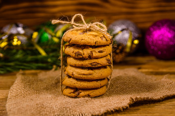 Stack of the chocolate chip cookies on sackcloth in front of christmas decorations