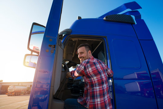 Shot of motivated smiling middle aged truck driver entering his semi truck long vehicle. Happy trucker. Transportation service.