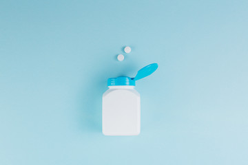 Pills scattered out the bottle on the blue background