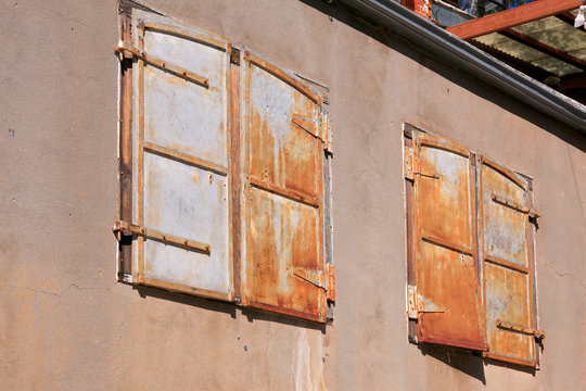 Two sets of rusting metal window shutters attached to a building in Bisbee, AZ