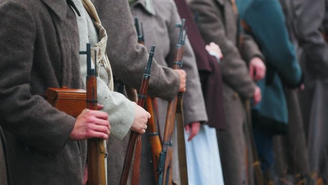 Men soldiers in warm coats standing in the row holding guns - autumn time