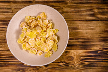 Ceramic plate with cornflakes on a wooden table. Healthy eating. Top view