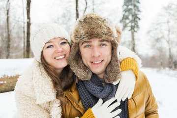 happy young couple spending time together in winter forest