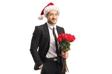 Handsome young man in a suit holding a bunch of red roses for Christmas