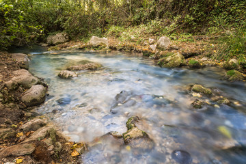 Naklejka na ściany i meble Mountain stream of clean and clear waters flowing between rocks.