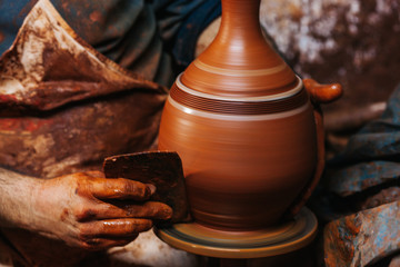 Hands of making clay pot on the pottery wheel ,select focus, close-up.