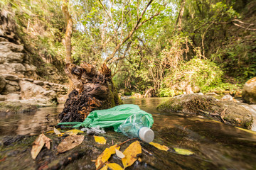 Abandoned garbage on the shore of a stream of clean water.