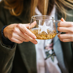 The girl is holding herbal tea.  a cup of linden tea