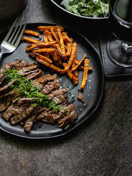 Black garlic seasoned skirt stake with sweet potato and iceberg cucumber salad in a bowl
