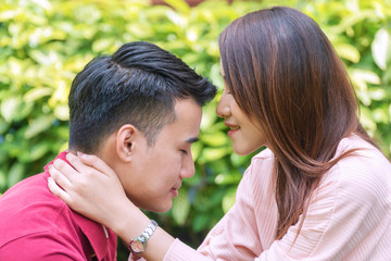 Fototapeta premium Charming young woman kiss forehead her boyfriend with love while sitting in the garden. Sweet romantic young couple embracing together at home. Relationship lover concept.