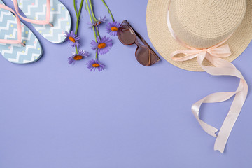 Summer subject photography. A hat, flip-flops and sunglasses on a purple background