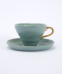 Empty green ceramic coffee or tea cup and saucer with golden handle isolated on white background