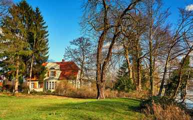 Fototapeta na wymiar Old idyllic house in the woods between trees.