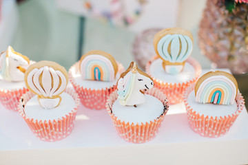Unicorn sugar cookies decorated with royal icing and food glitter on a white background. various cookies on white serving. unicorn, cloud, flying balloon and rainbow.