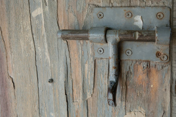 Old cracked paint on a gray wood panel. Creative vintage natural background. Old metal latch. Bolt.