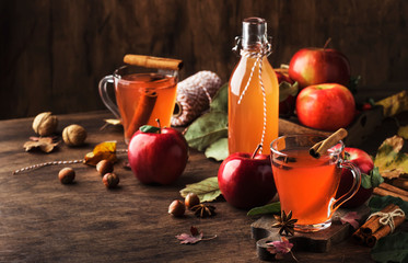 Hot mulled apple cider with with cinnamon sticks, cloves and anise on wooden background....