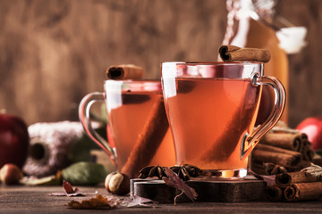 Hot mulled apple cider with with cinnamon sticks, cloves and anise on wooden background. Traditional autumn, winter drinks and cocktails