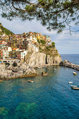 Fototapeta na wymiar Beautiful view of colorful residential buildings and a bay with boats in the village of Manarola, Italy, National Park of the Cinque Terre