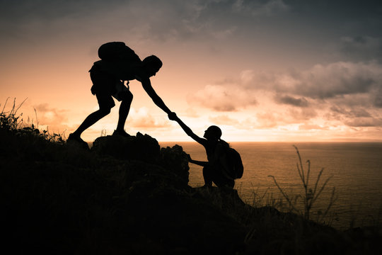 Male mountain climber giving his hand to help his partner.Giving a helping hand. 