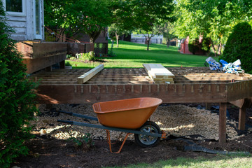 A Wheelbarrow in front of a Backyard Home Deck in the Process of being Disassembled