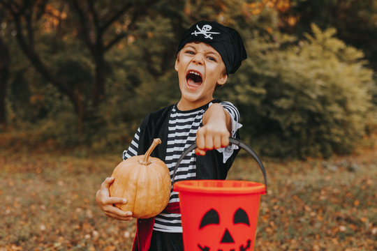 Disguised kid standing with pumpkin and bucket