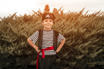 Cute boy in pirate costume standing by bushes