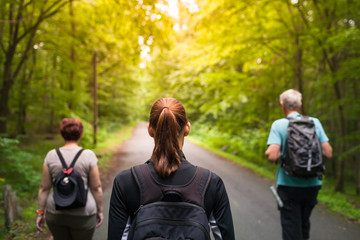 Family of three walking on path through the forest.